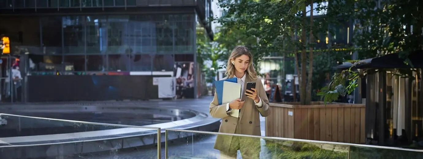 Porträt einer Geschäftsfrau im Anzug, die ein Mobiltelefon benutzt und in der Innenstadt auf einen Geschäftspartner wartet.